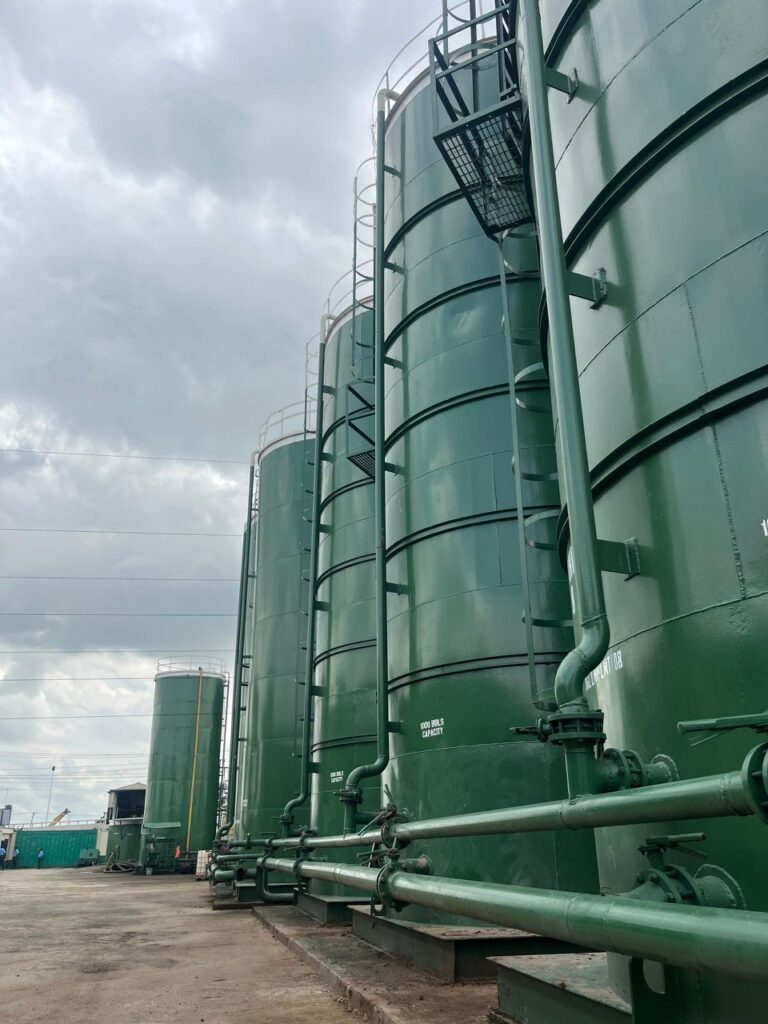 Row of tall green Oilchem storage tanks with connecting pipework